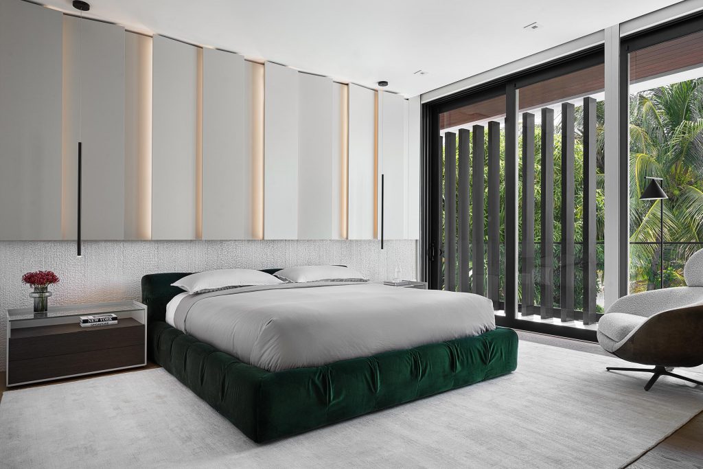 Nature inspired master bedroom with velvet green bed, custom headboard wall in sand colors with top half in custom woodwork with led illumination and bottom half in rough stone, sand plain rug, and large wood and glass nightstands