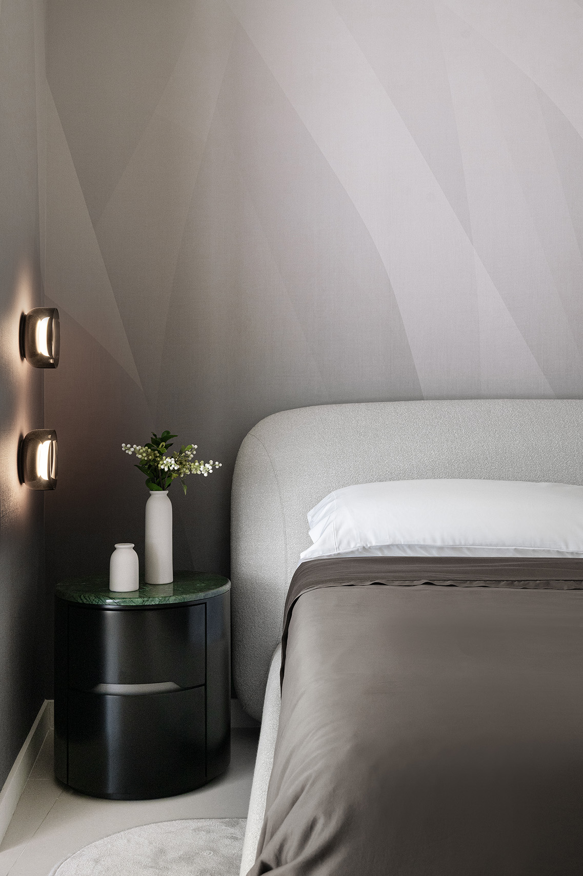 Bedside detail in FM Apartment with upholstered bed, green stone nightstand, and soft wall lighting.