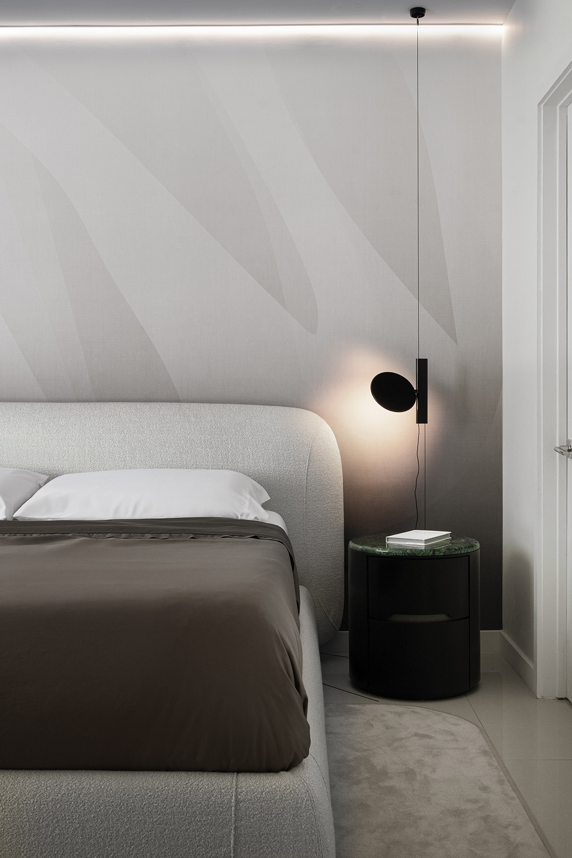 Primary bedroom in FM Apartment with upholstered bed, mural wallcovering, suspended bedside light, and green stone nightstand.