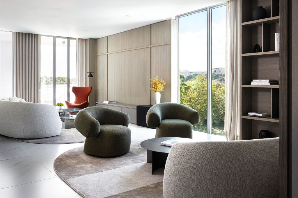 Open great room with organic seating, custom bookshelf, ash wood media wall, and panoramic tree canopy views